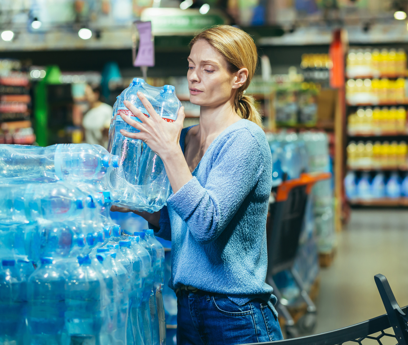 Woman shopping for bottled water in store.